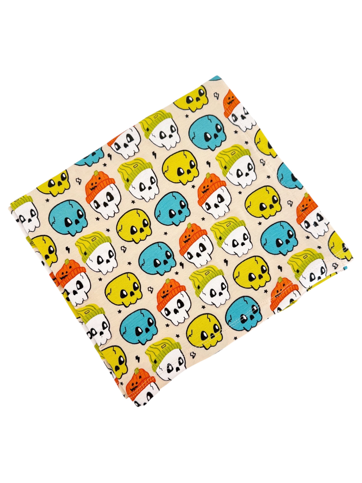 Colorful fabric featuring cartoon skulls and hats in blue, yellow, orange, and green on a light background.