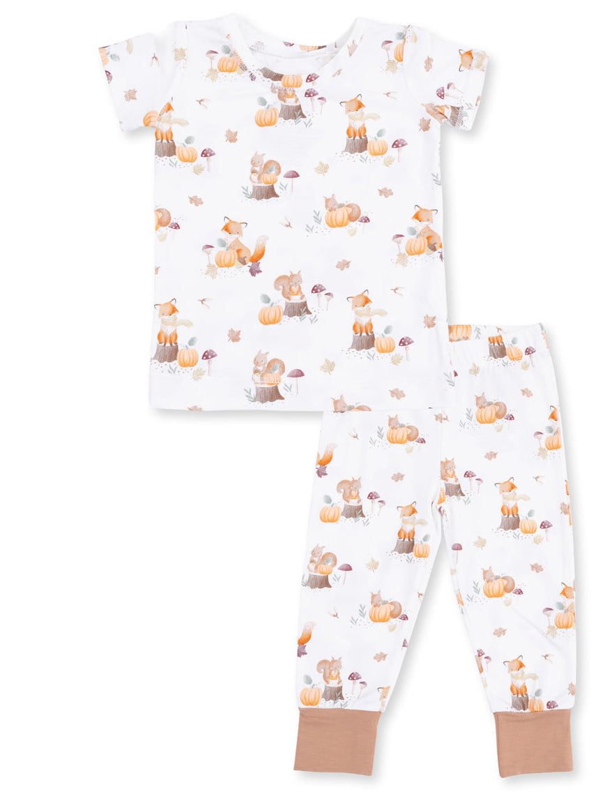 Children's pajama set featuring whimsical woodland animals, pumpkins, and mushrooms in warm autumn colors.