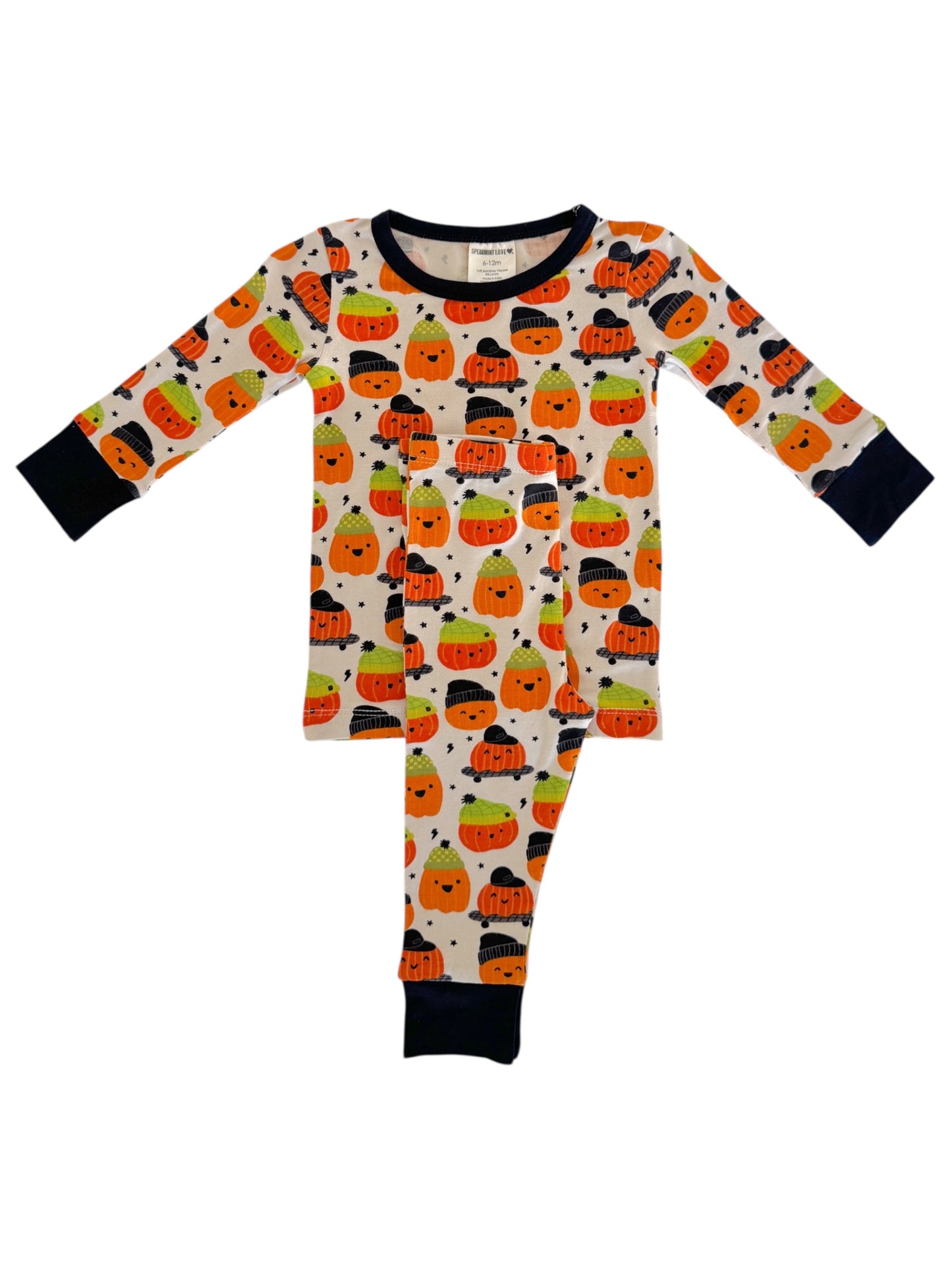 Children's Halloween pajamas featuring cute pumpkin and ghost patterns in orange, green, and black on a light background.