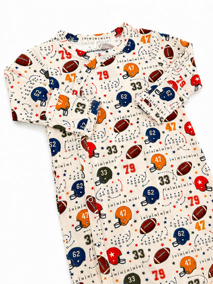 Child's football-themed sleepwear featuring helmets, numbers, and stars in vibrant colors on a cream background.