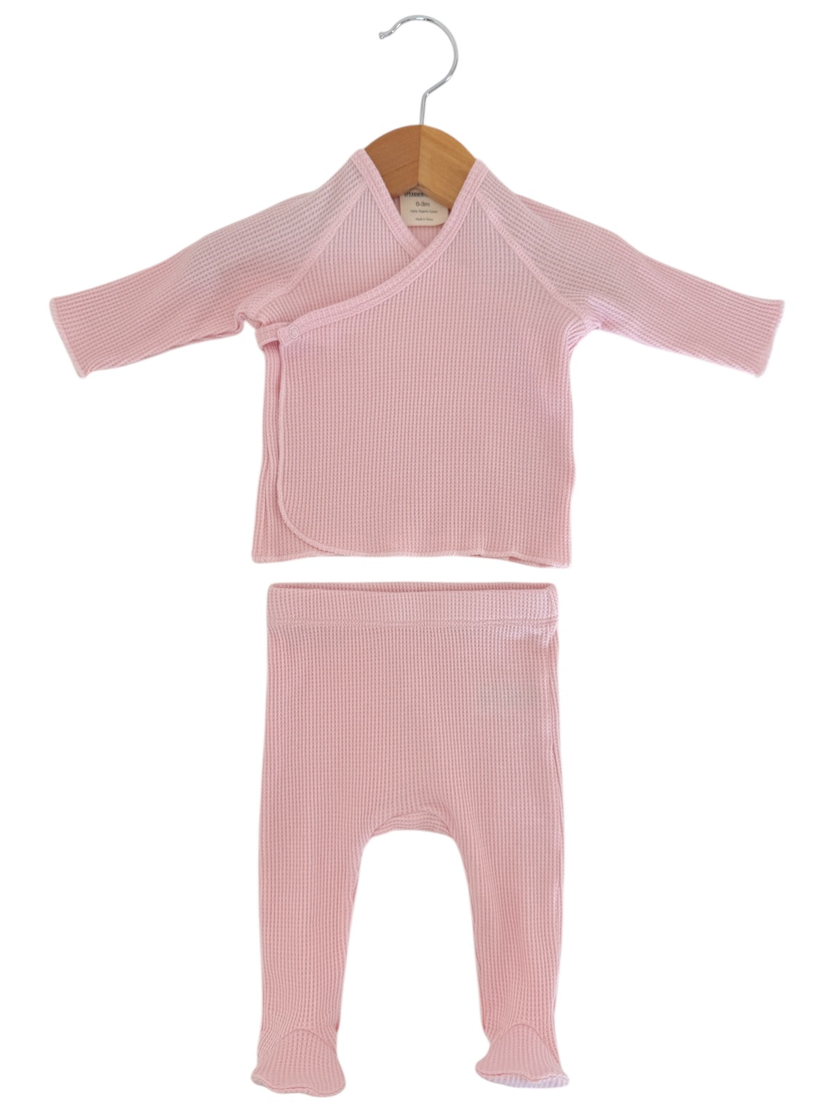 Pink baby outfit featuring a long-sleeve wrap top and matching leggings, displayed on a wooden hanger.