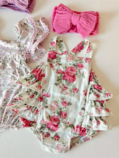Floral baby romper with ruffled sleeves, paired with a pink bow headband and a second floral outfit.