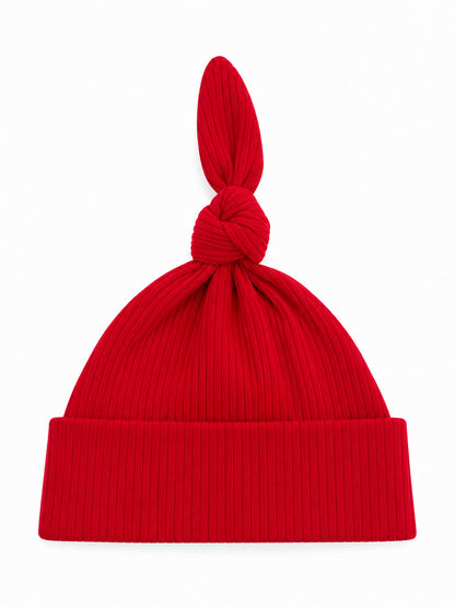 Red ribbed knit beanie with a twisted top knot, displayed against a white background.