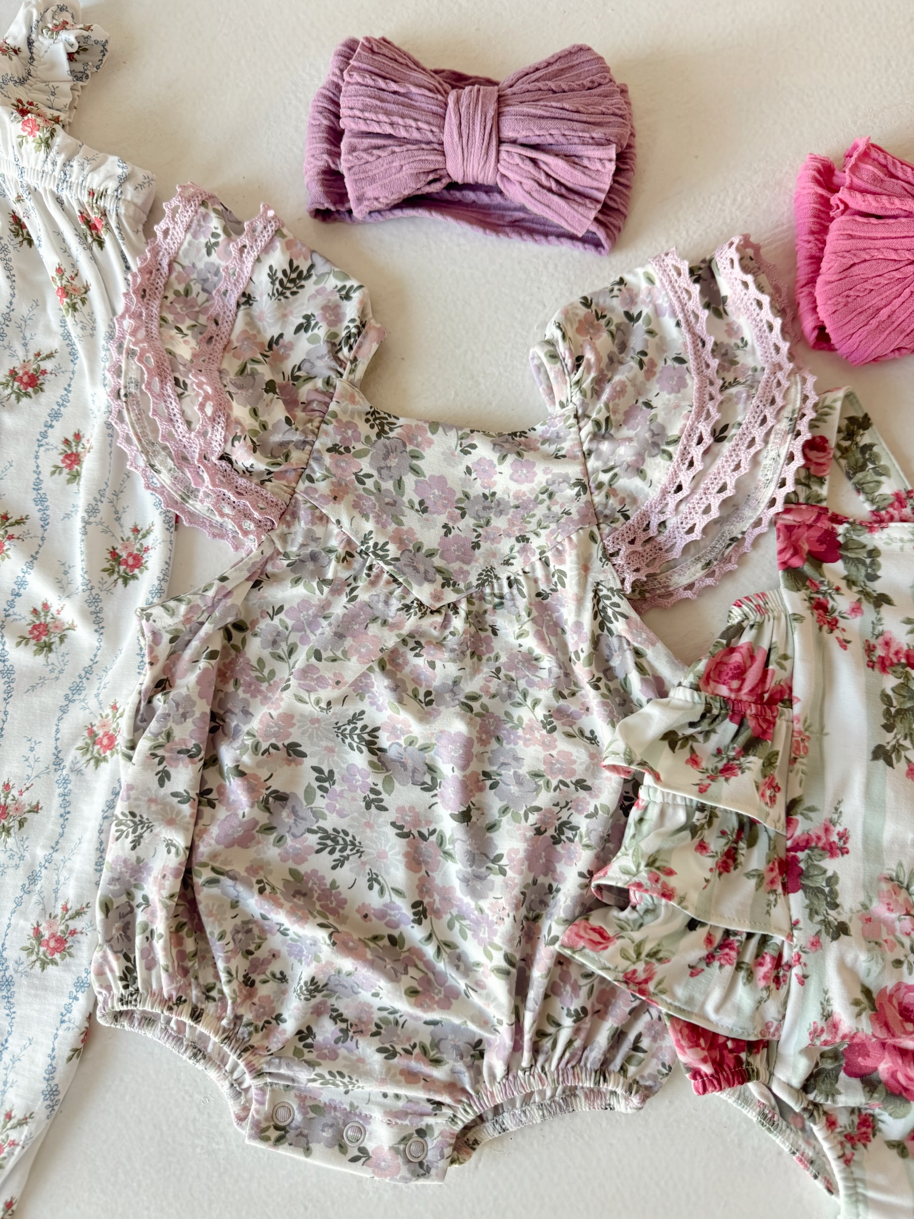 Baby girl outfits featuring floral patterns and coordinating hair accessories in soft pastel colors.