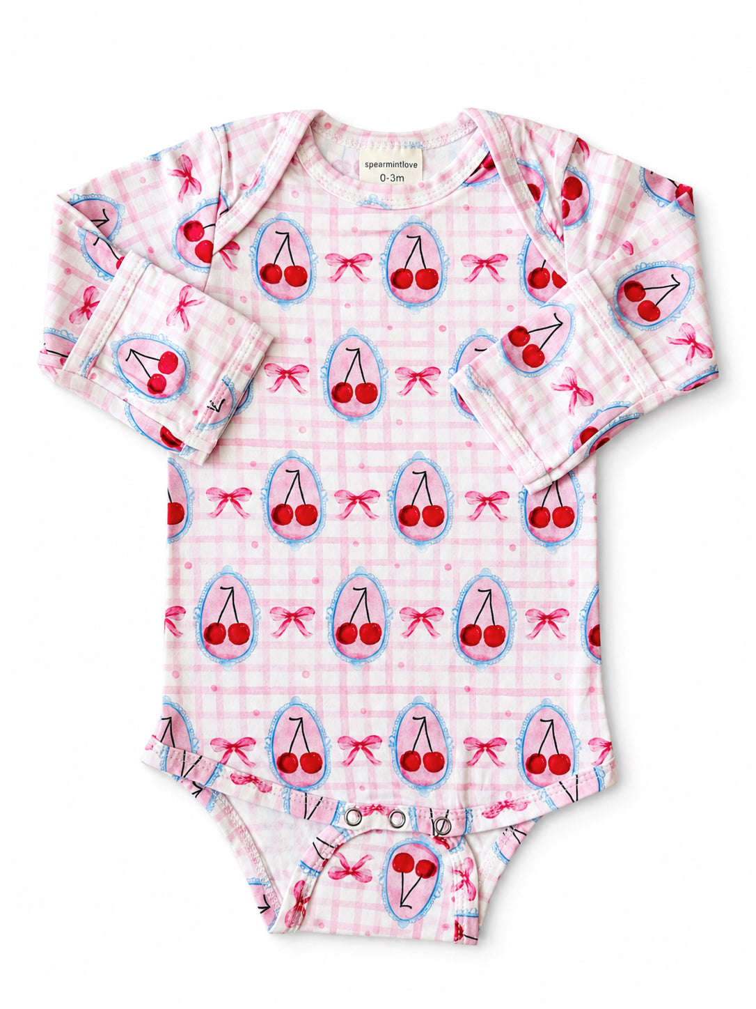 Pink baby onesie with cherry print and bows, featuring long sleeves and snap closures at the bottom.