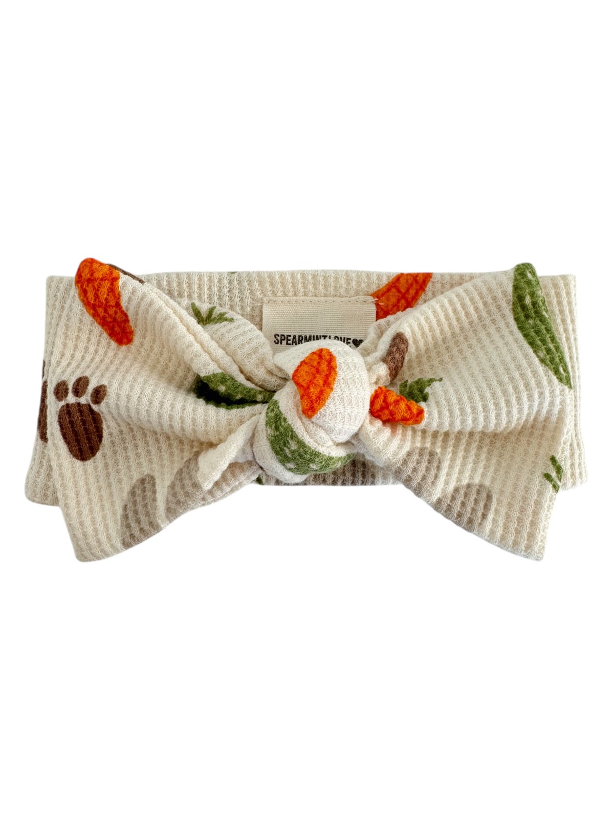 Cream fabric headband with a knot, featuring carrot and paw print patterns in orange and green.