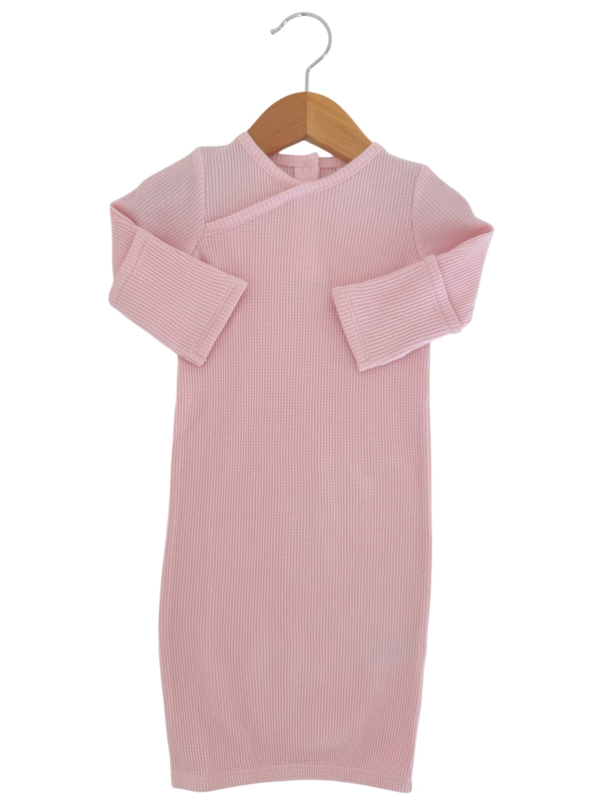 Pink baby dress with ribbed texture, displayed on a wooden hanger against a white background.