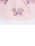 Pink tulle fabric adorned with shiny sequined bows. Elegant and playful design for children's wear.