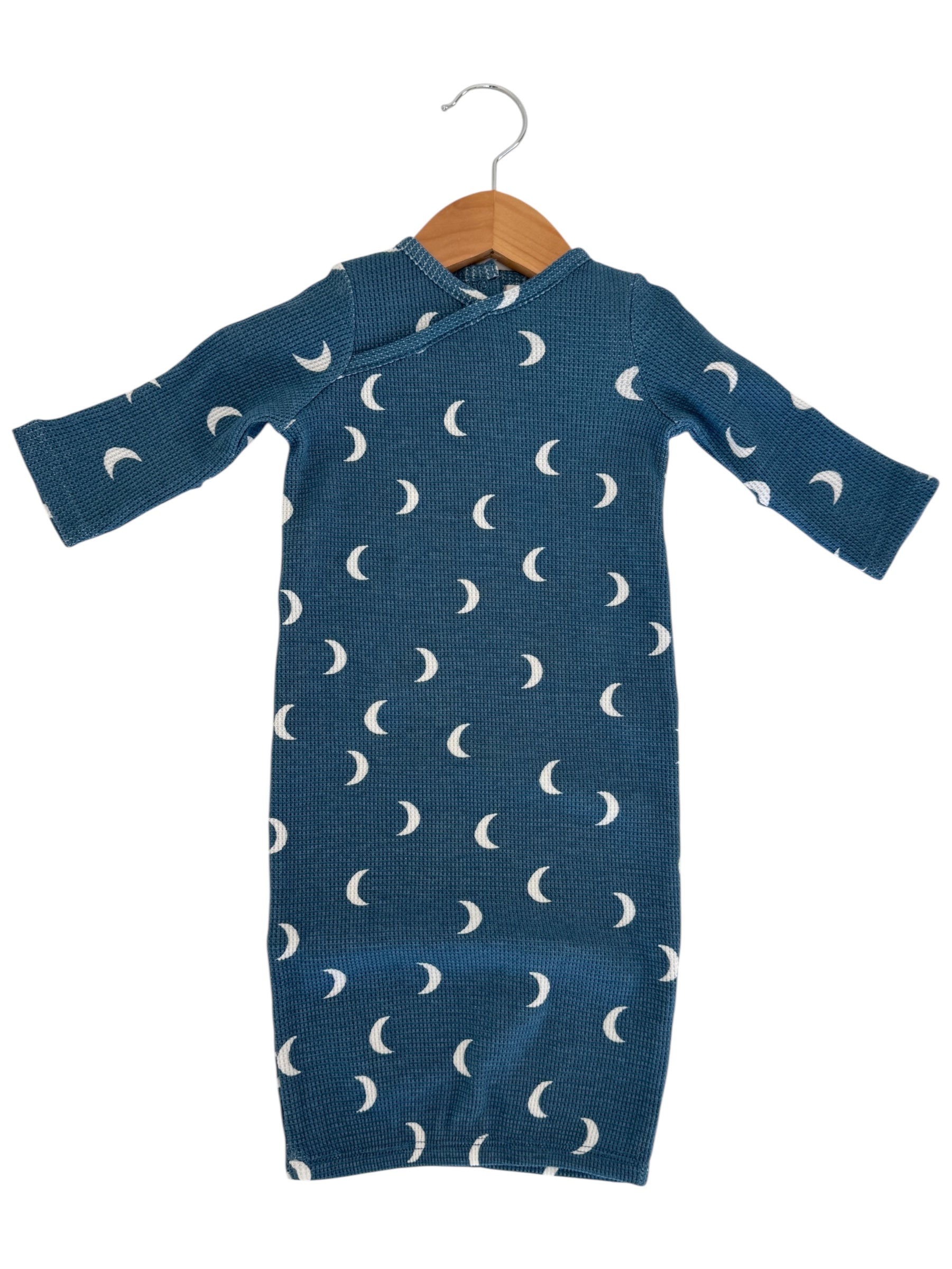 Blue baby outfit with white crescent moon pattern, displayed on a wooden hanger.