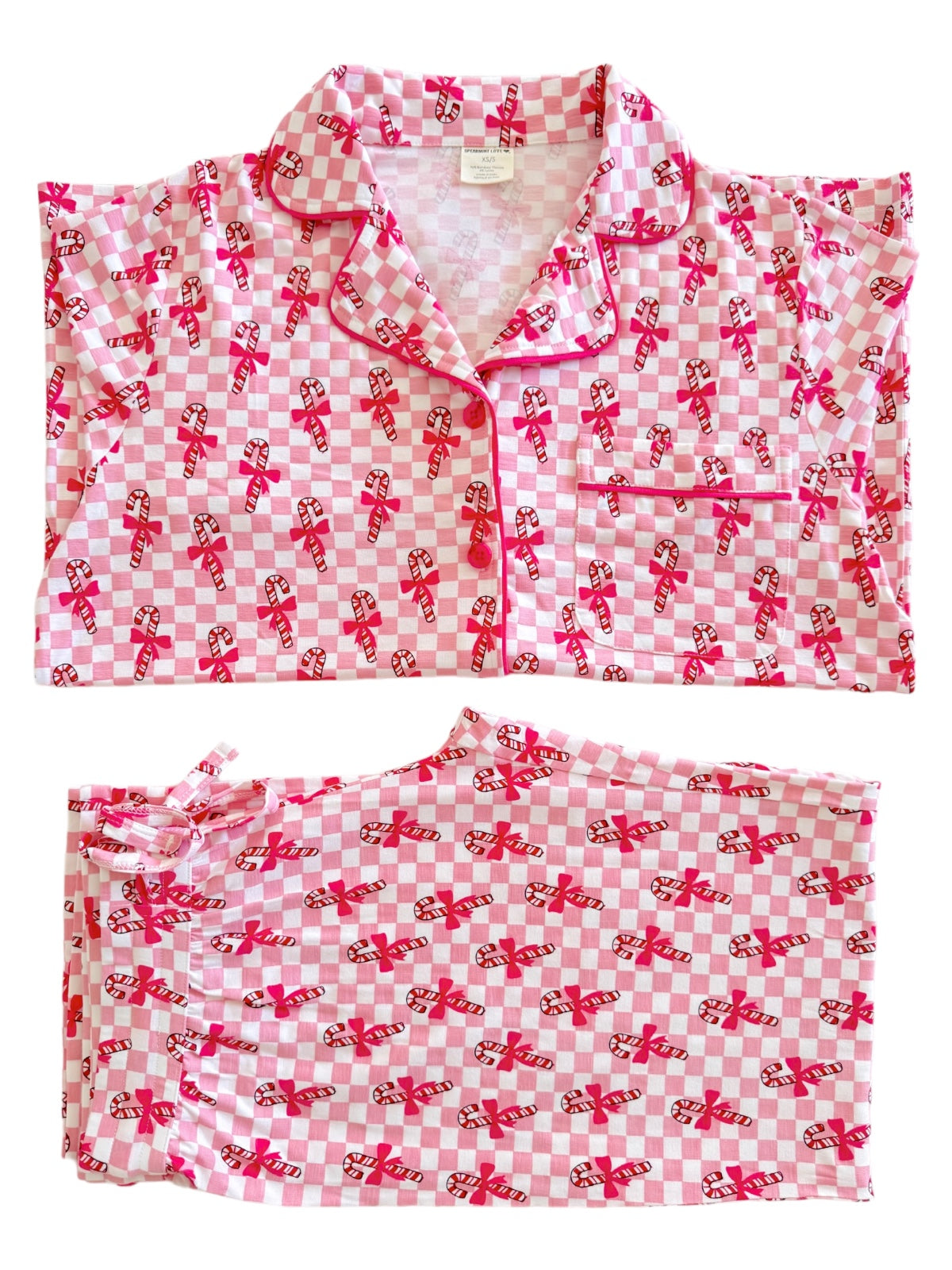 Pink and white checkered pajamas with candy cane and bow patterns, laid flat for display.