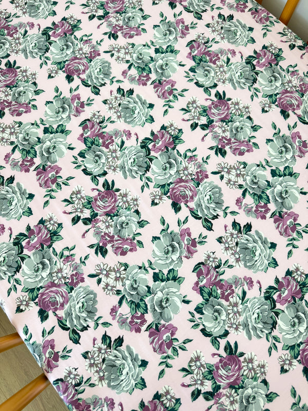 Floral pattern with roses and greenery on a pink background, perfect for home decor or textile designs.