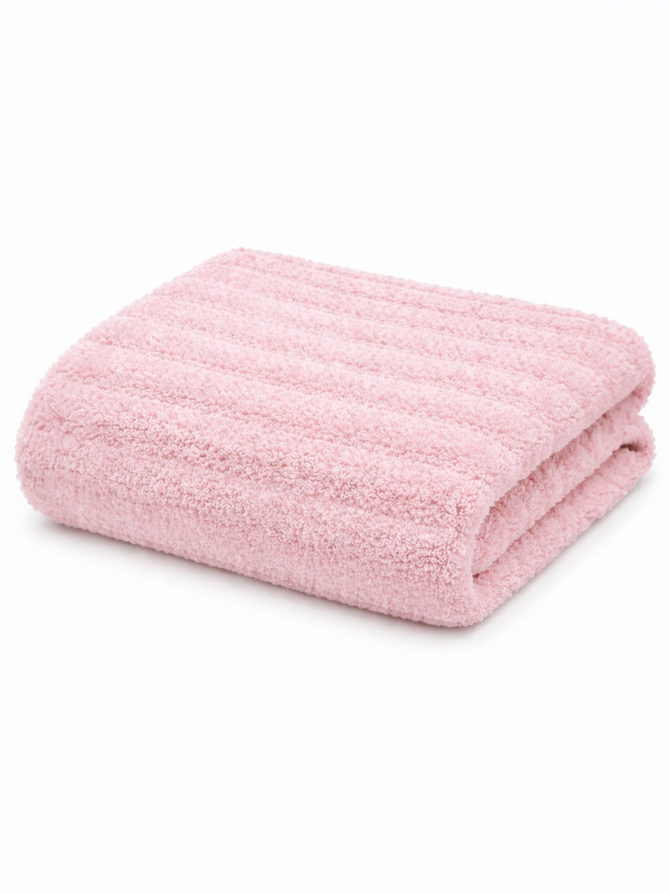 Soft pink bath towel neatly folded, featuring a textured design on a white background.