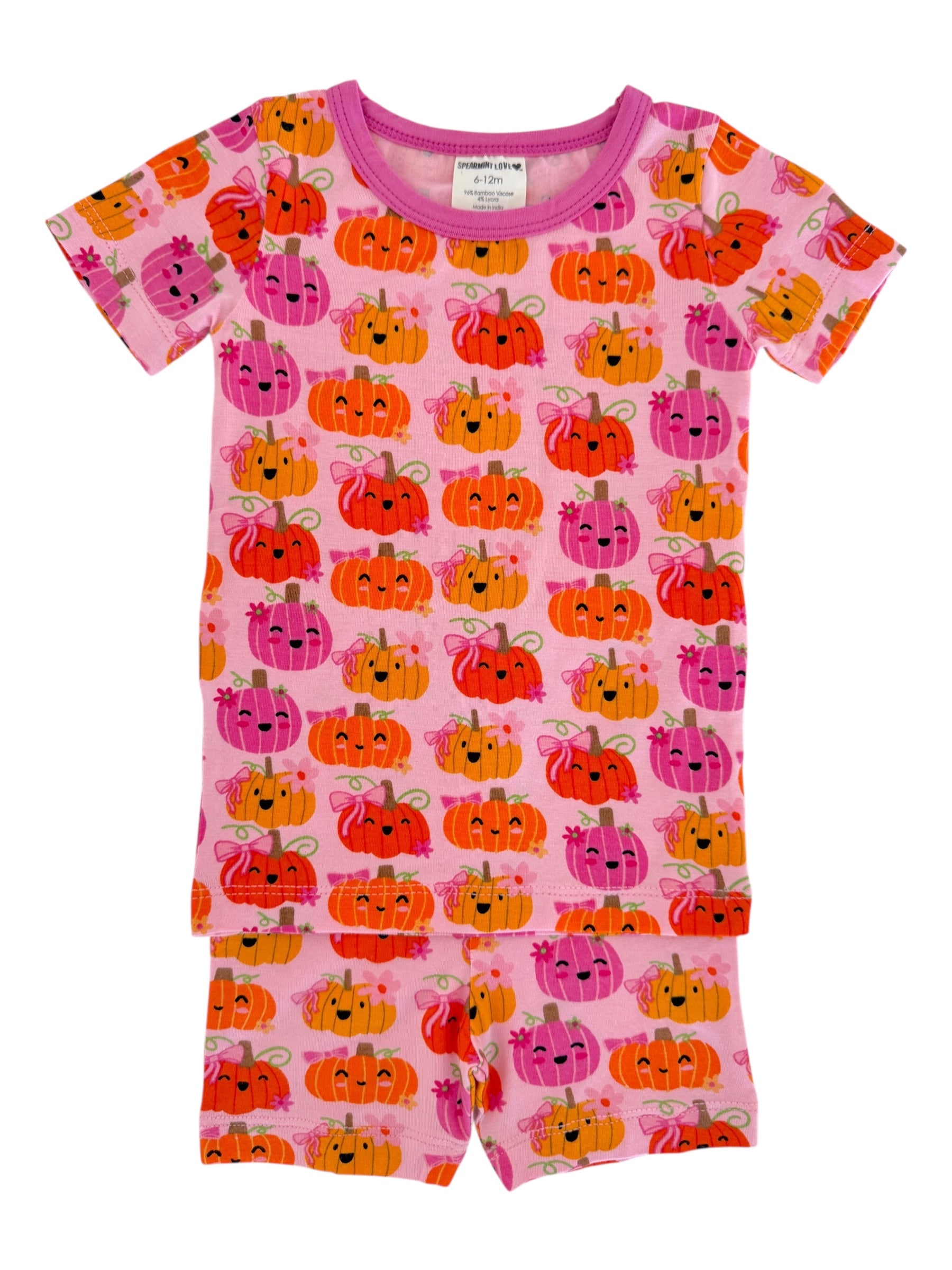 Pink toddler pajamas featuring a pattern of colorful, smiling pumpkins on a light pink background.