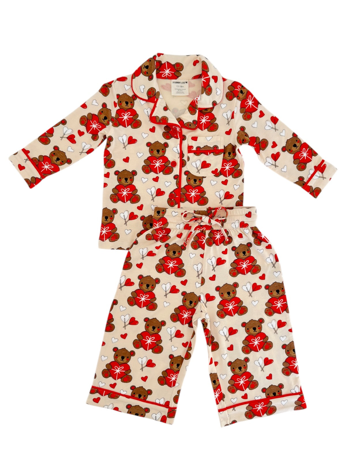 Children's pajama set featuring a playful bear and heart pattern in red, white, and beige colors.
