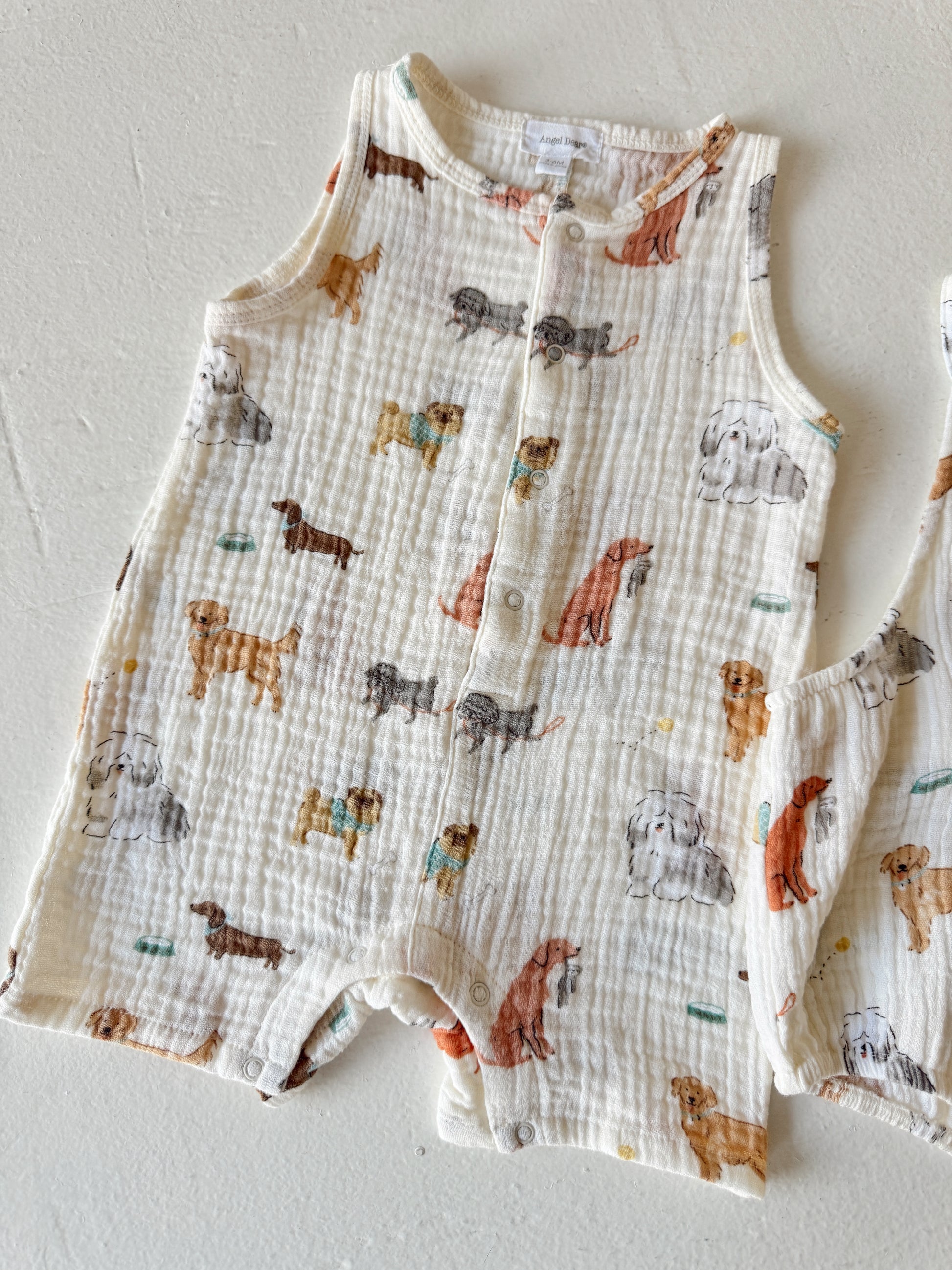 Toddler outfit with a dog print, featuring various dog breeds on a light fabric background.