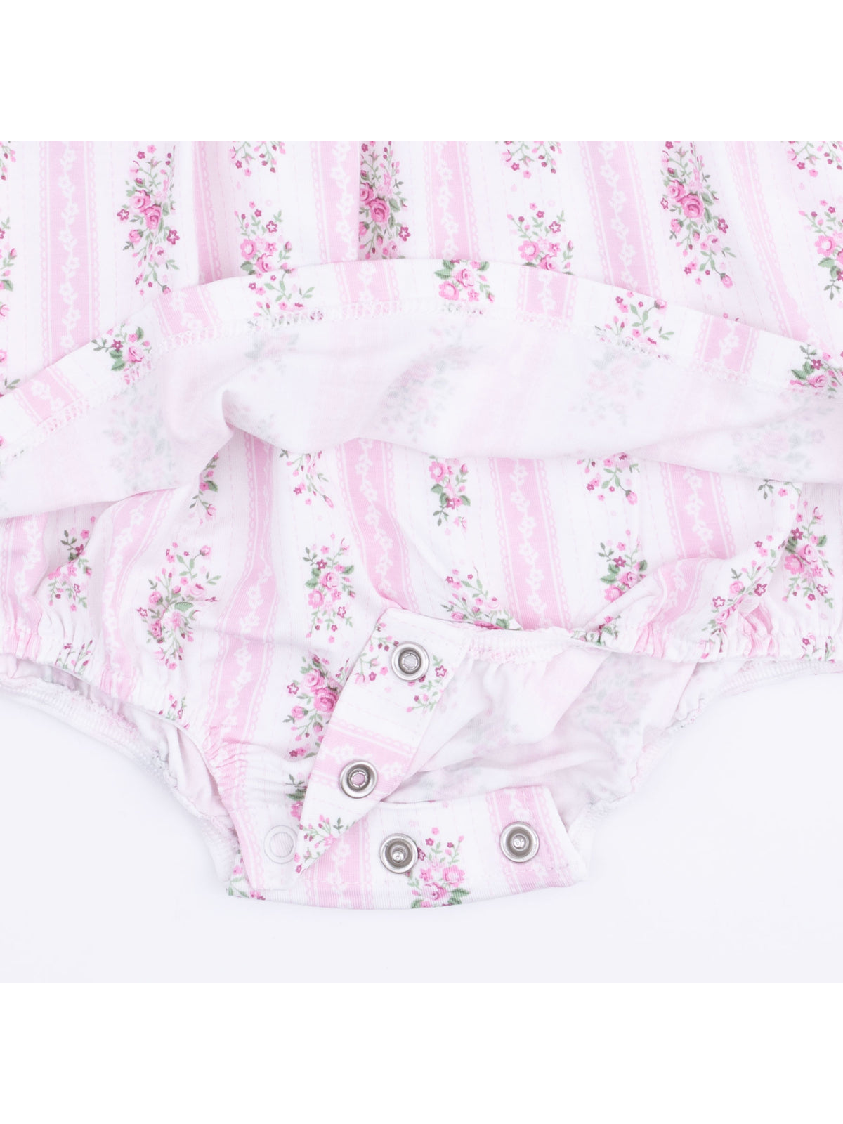 Pink floral baby onesie with button snaps and soft fabric draped elegantly.