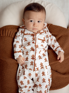 Baby in gingerbread-themed pajamas lying on a cozy, textured blanket.