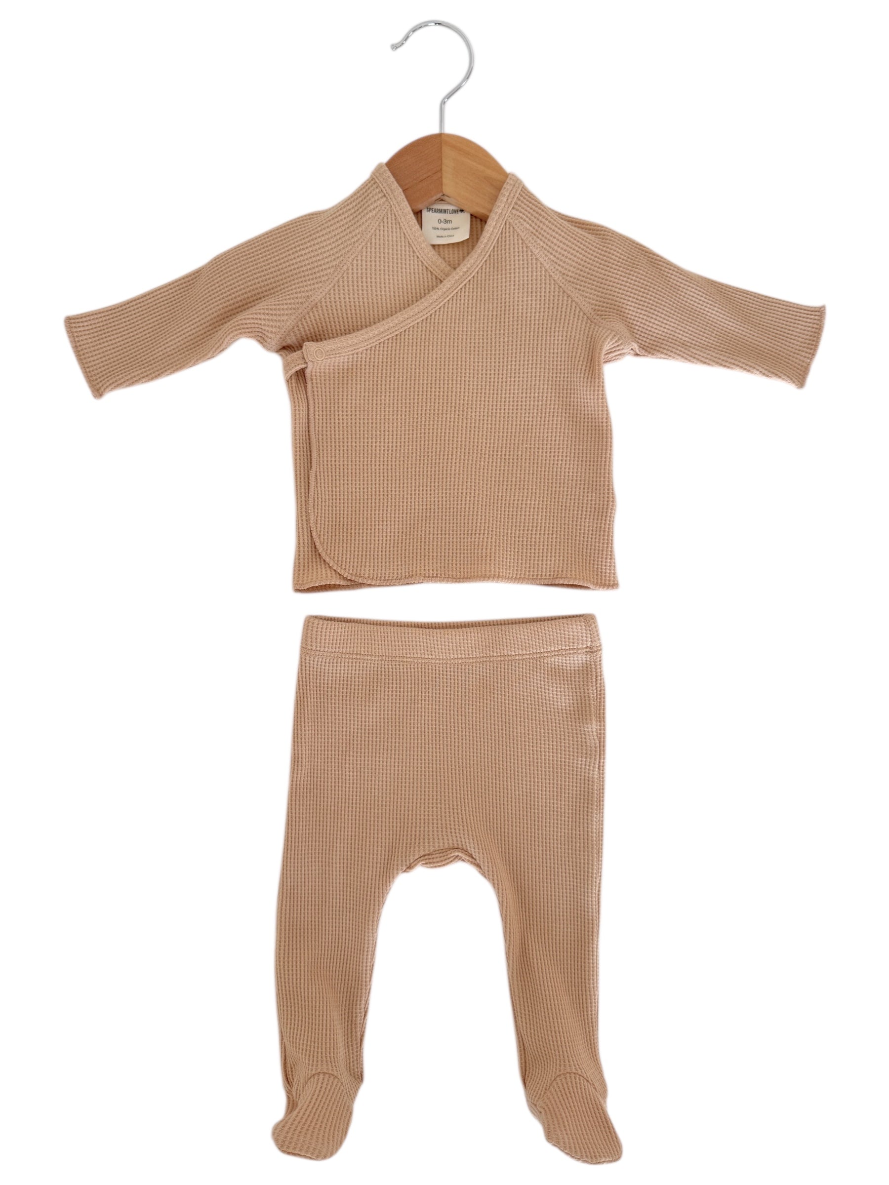 Beige infant wrap top and matching footed pants on a hanger, made from soft ribbed fabric.