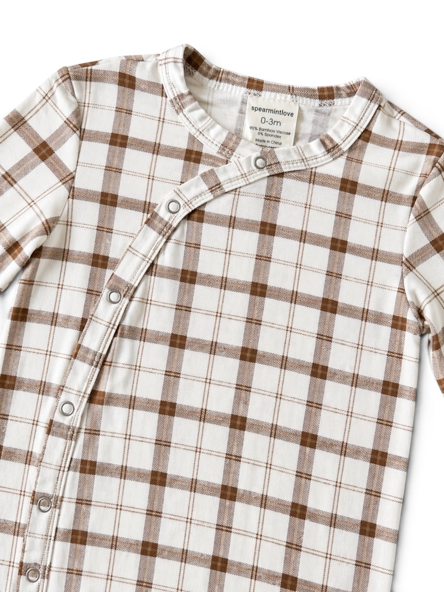 White and brown plaid infant onesie with snap buttons, labeled size 0-3 months.
