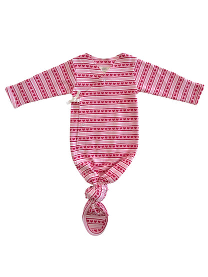 Baby sleep sack in pink with heart patterns, featuring long sleeves and a knotted bottom for easy diaper changes.