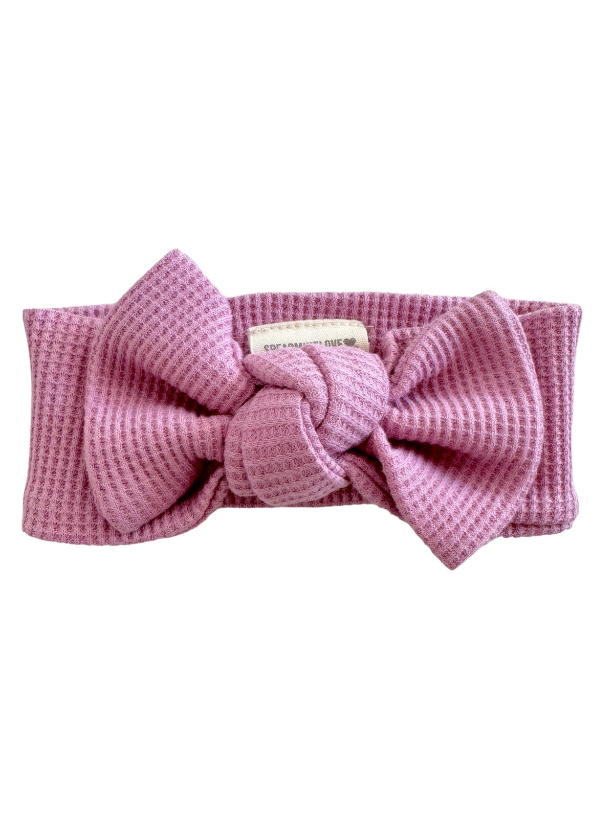 Pink textured headband with a large bow detail at the front. Ideal accessory for casual or stylish outfits.