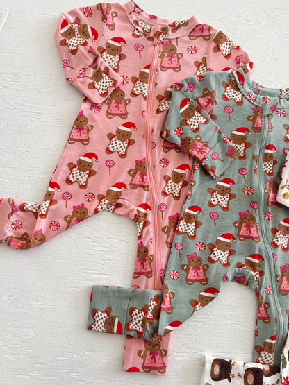 Two holiday-themed children's onesies in pink and green, featuring gingerbread figures and candy designs.
