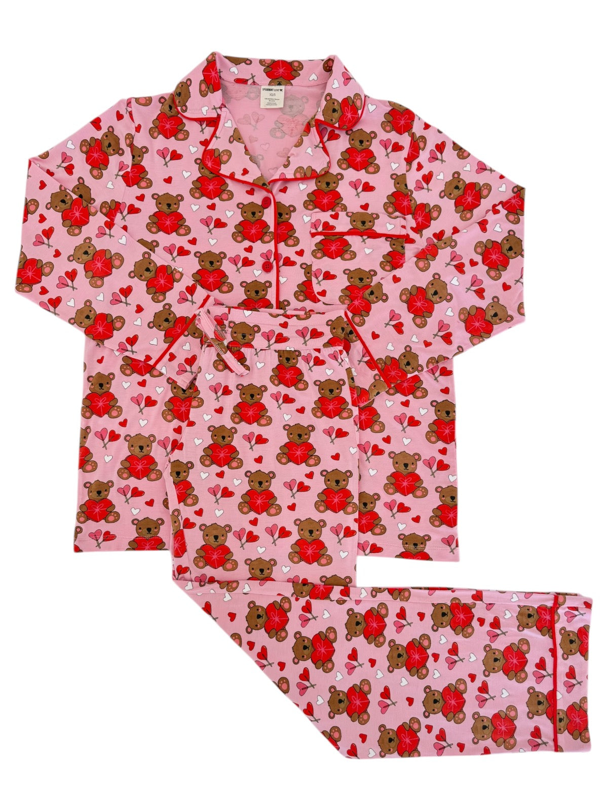 Pink pajama set featuring bears and hearts, perfect for cozy nights. Includes a button-up top and matching pants.
