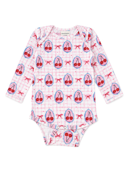 Pink long-sleeve baby onesie with cherry and bow patterns on a checkered background.