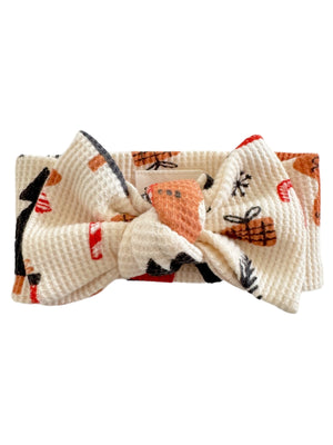 Light cream headband with a large bow and colorful patterned designs.