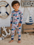 Smiling child in nautical-themed pajamas poses on a sandy beach background with decorative elements.
