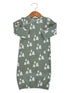 Green infant outfit with white tree pattern, hanging on a wooden hanger against a white background.