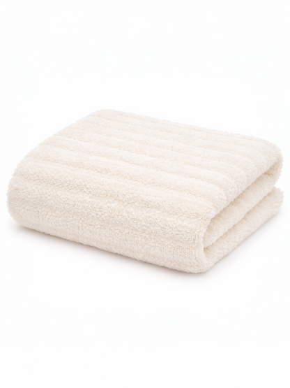 Folded cream-colored towel with a textured surface on a white background.