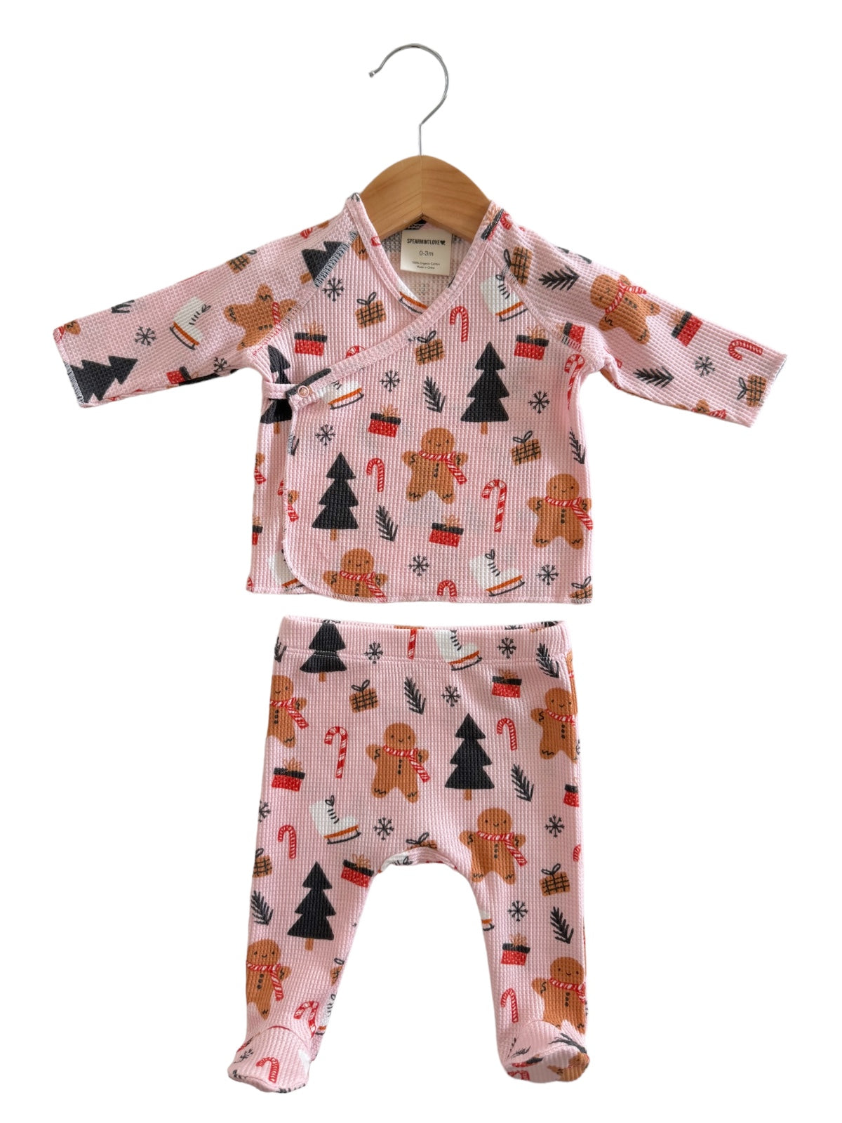 Pink baby outfit with gingerbread, candy canes, and trees, featuring a wrap top and matching pants.