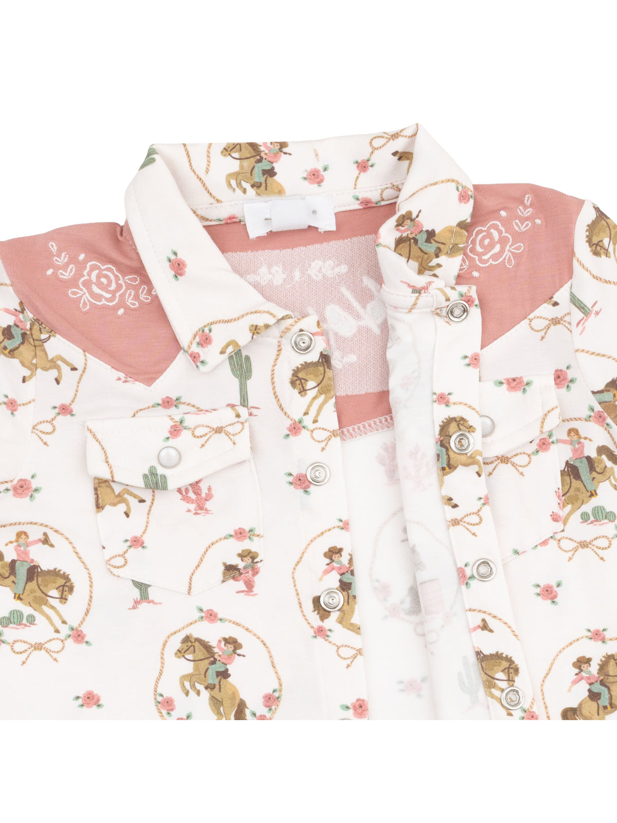 Patterned western shirt featuring cowboys and flowers, with pink accents and button closure.