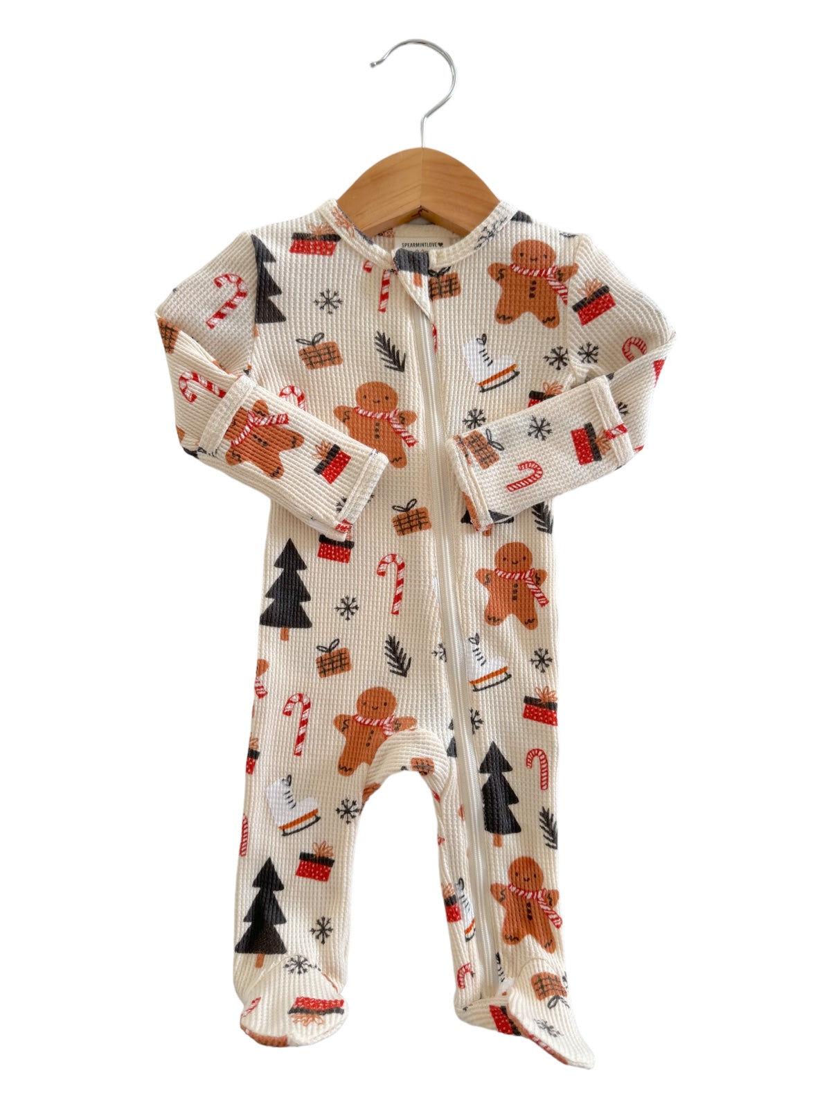 Holiday-themed baby onesie with gingerbread men, candy canes, and pine trees on a light background.