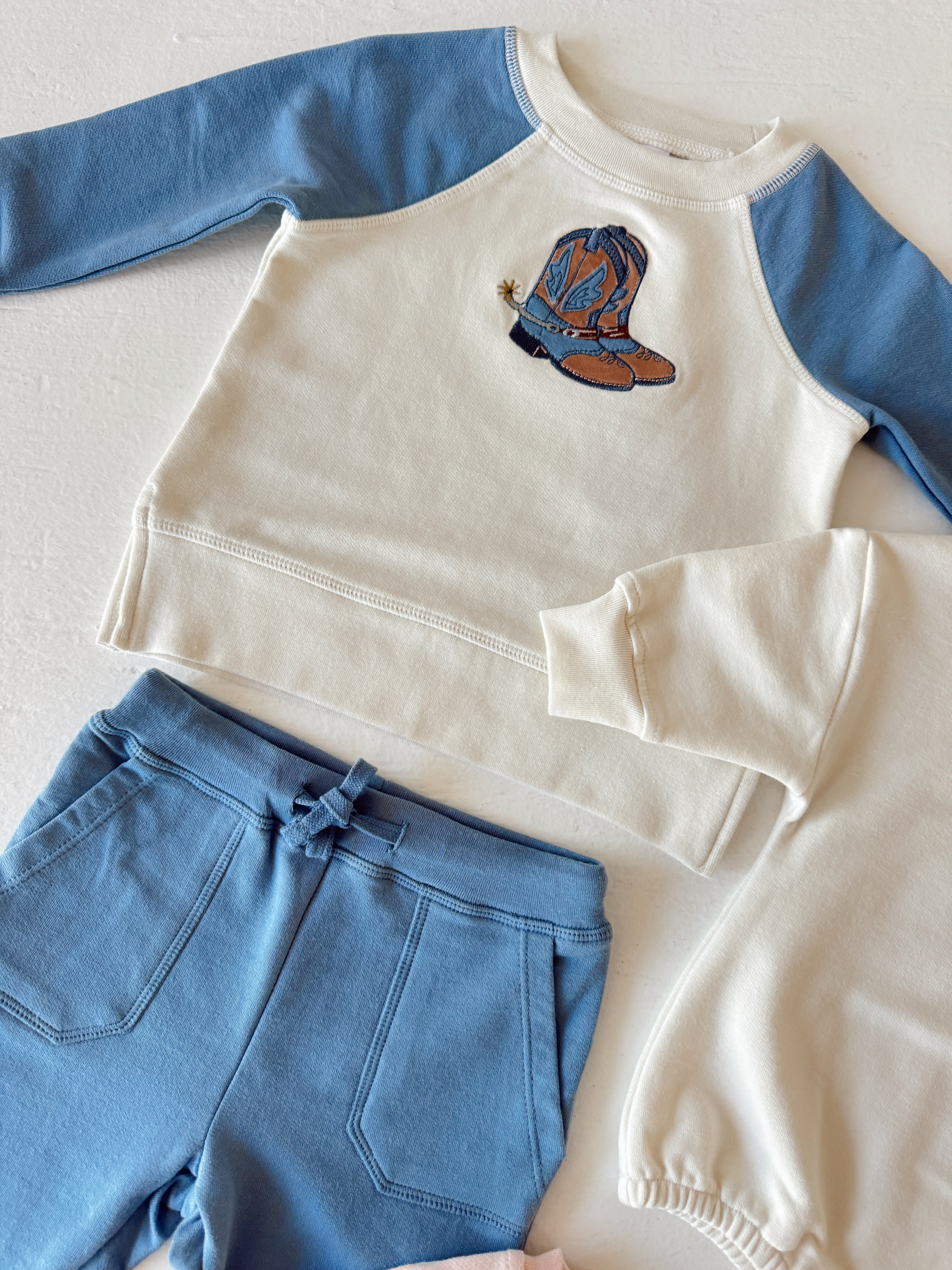 Blue and white children's clothing set featuring a cowboy boot design on a sweat shirt and matching pants.