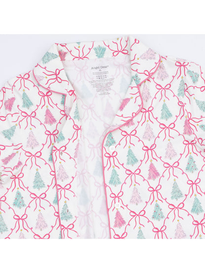 White shirt with pink bows and colorful Christmas trees, showcasing a festive pattern and a tag inside.