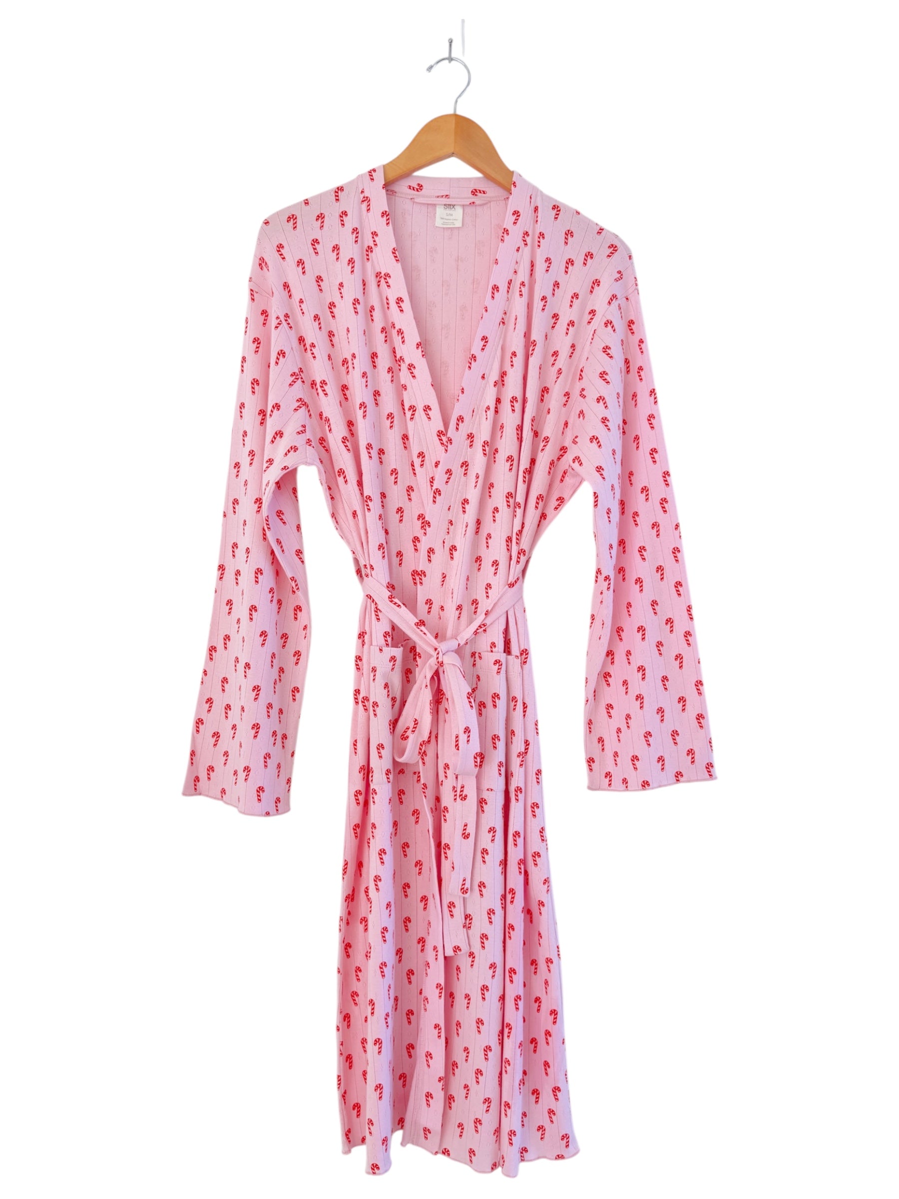 Pink robe with red pattern, long sleeves, and a tie closure, hanging on a wooden hanger.