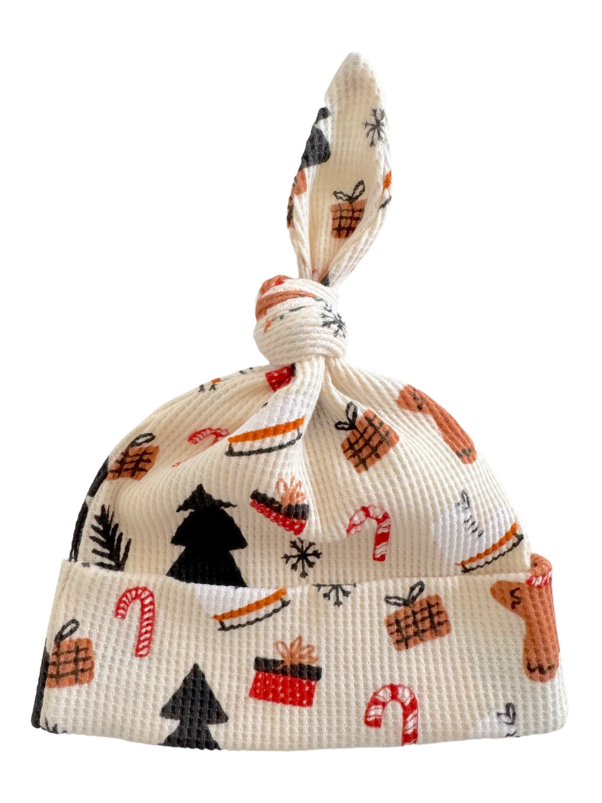 Knotted baby hat with festive patterns including trees, gifts, and candy canes on a white background.