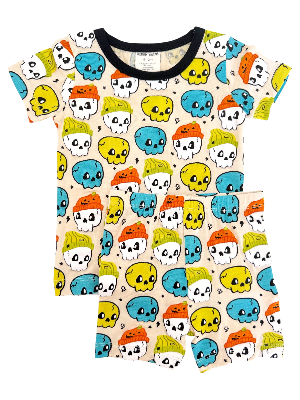Colorful children's pajamas featuring skulls with hats in yellow, blue, and orange on a cream background.