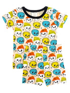 Colorful children's pajamas featuring skulls with hats in yellow, blue, and orange on a cream background.