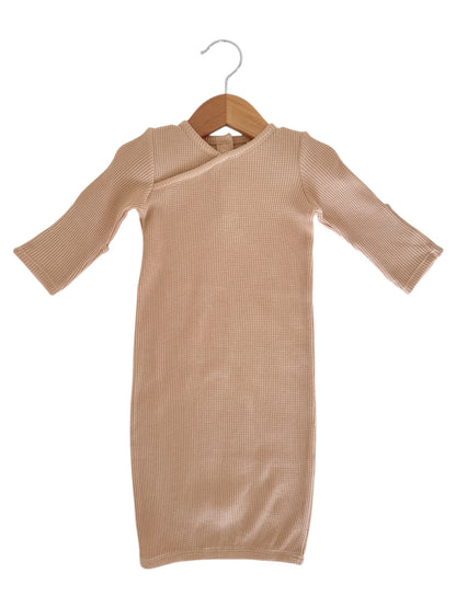 Beige ribbed dress with long sleeves hanging on a wooden hanger against a white background.