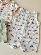 Two baby outfits: a fish-patterned onesie and a short-sleeved shirt with a crab design, laid on a light surface.