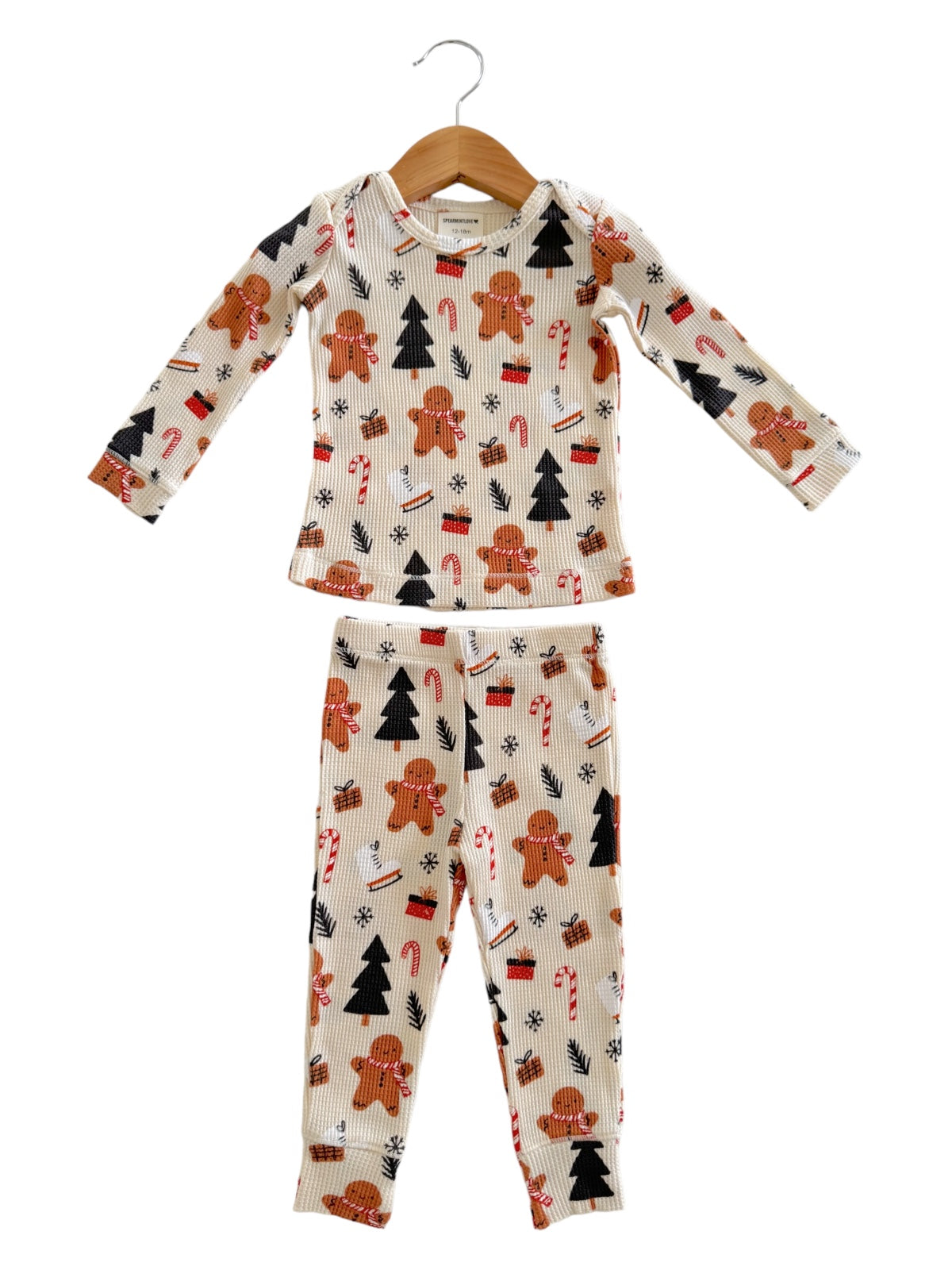 Children's holiday pajamas featuring gingerbread men, Christmas trees, and candy canes in a playful design.