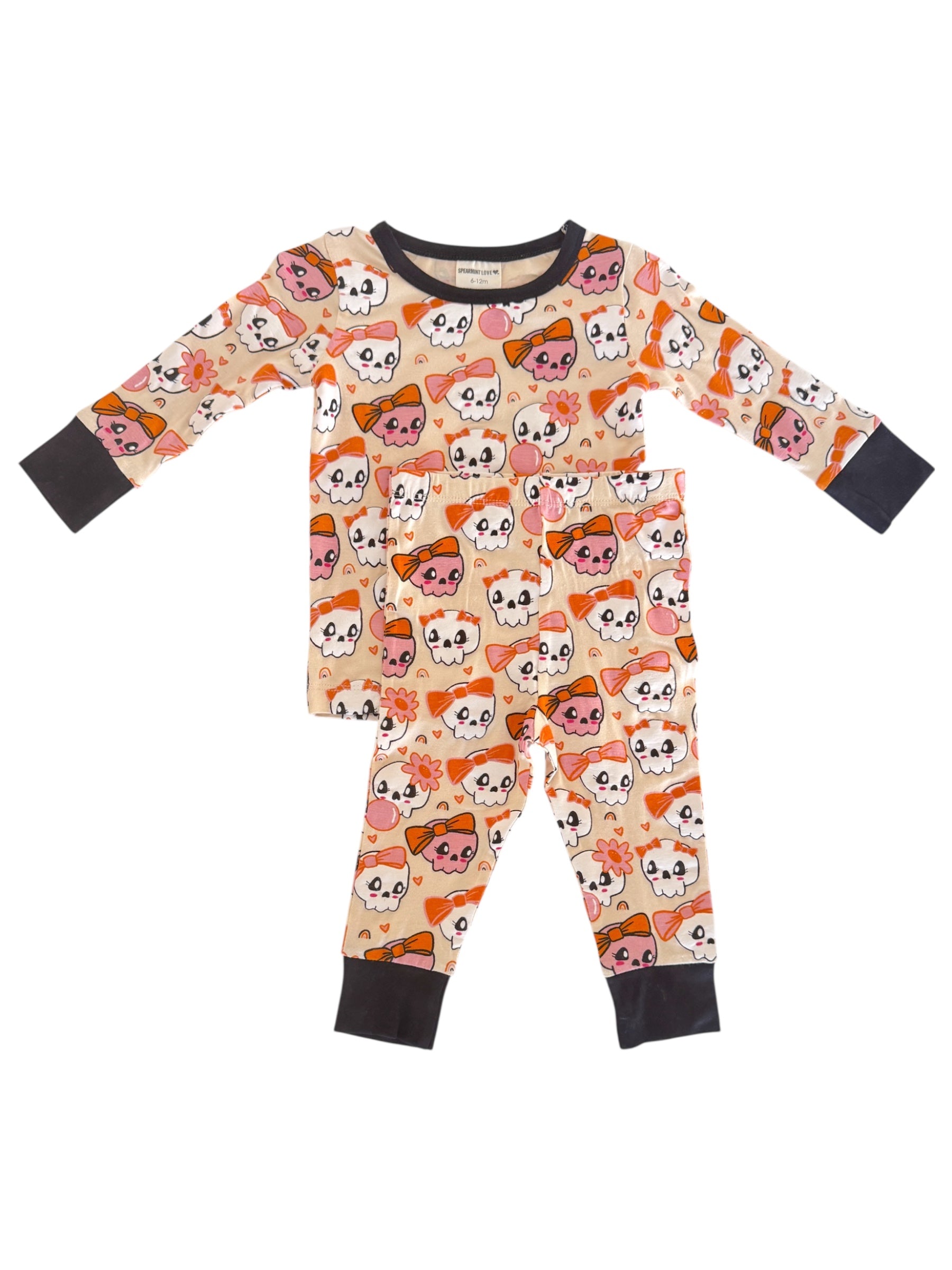 Colorful children's pajamas featuring playful skull and bow patterns in pink and orange.