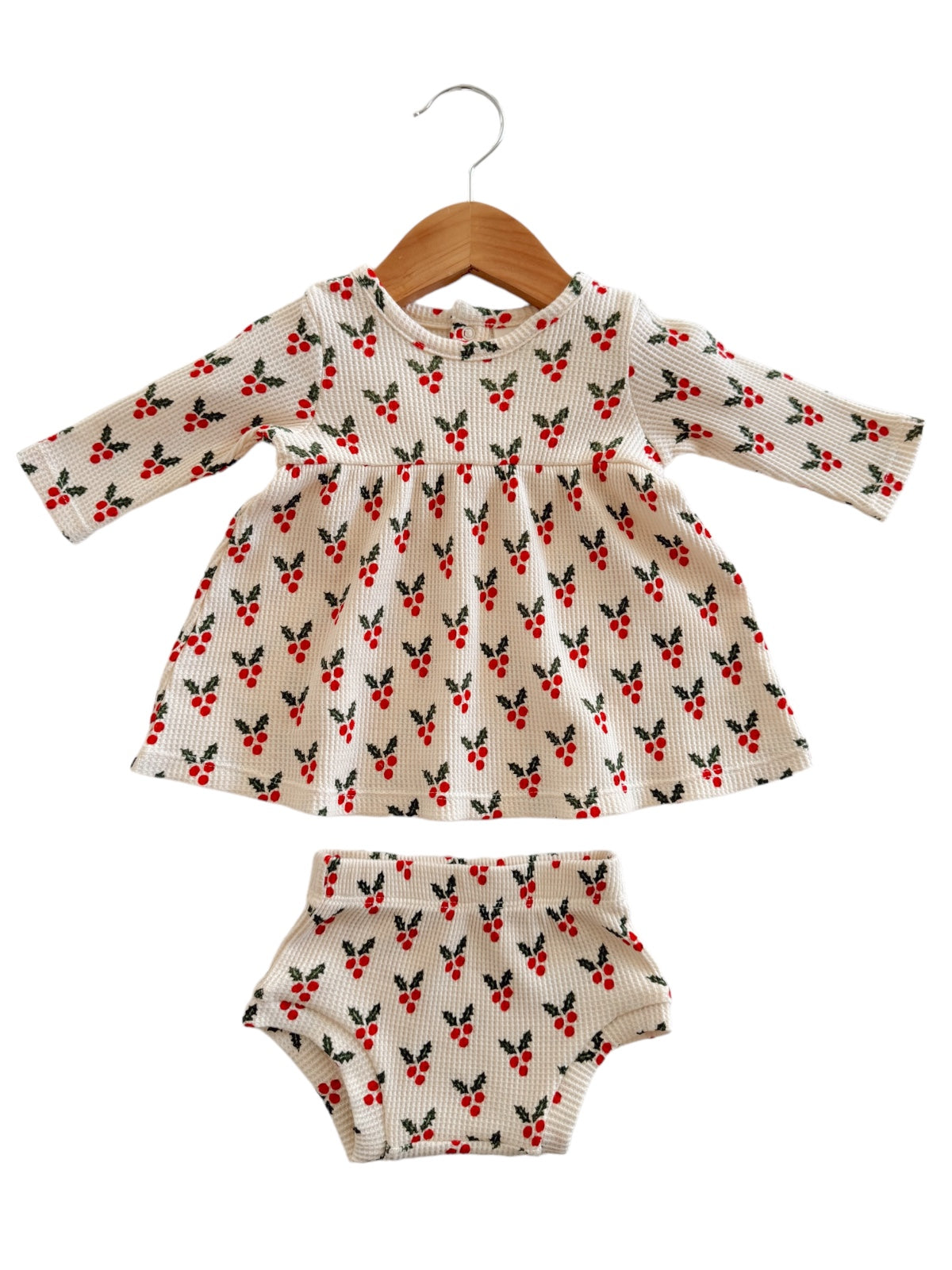 Girls' dress and matching bloomers with a floral pattern, hanging on a wooden hanger.