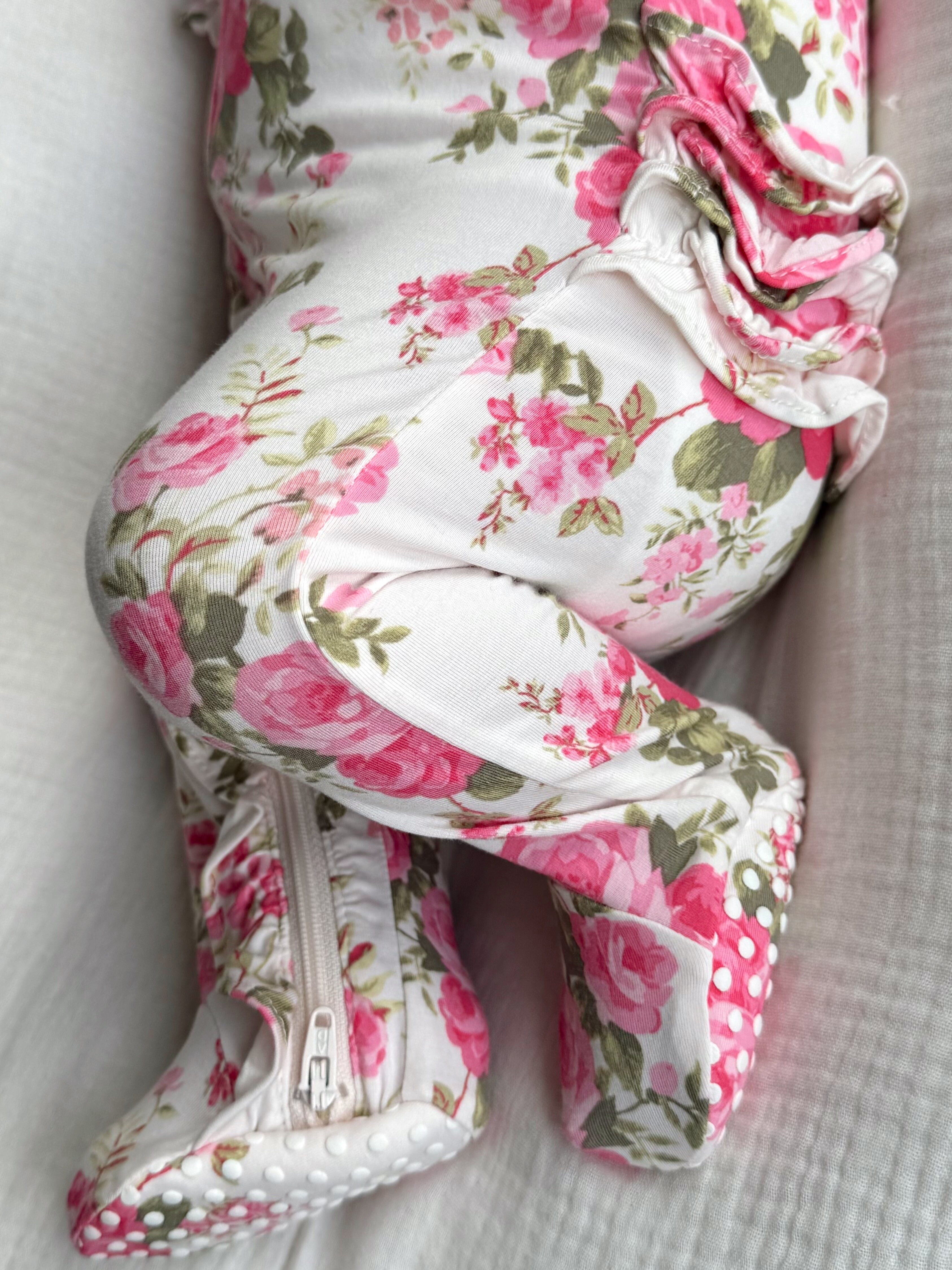 Close-up of a baby's leg in floral-patterned clothing with a zipper and textured soles.