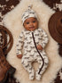 Smiling baby in horse-patterned outfit on soft fur with cowboy hat and boots nearby.