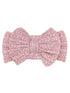 Pink fabric hair bow with textured pattern and a central knot detail. Ideal accessory for children or women's fashion.