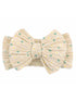 Beige hair bow with green and yellow floral design on a textured fabric. Ideal for stylish hair accessories.